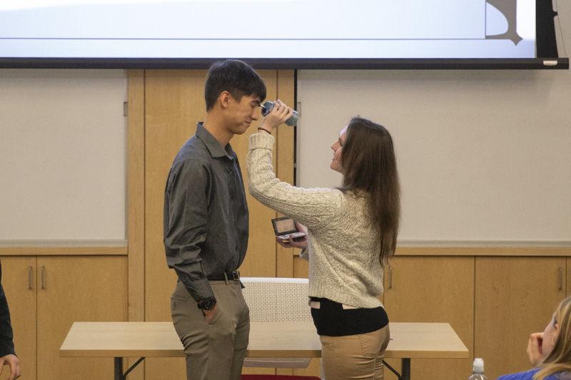 Female student presses makeup brush to male student's face