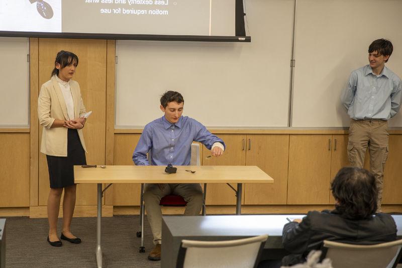 Three students present assistive utensil device to attendees