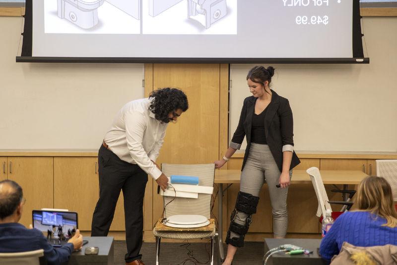 Female and male student present adaptive toilet lid opener 