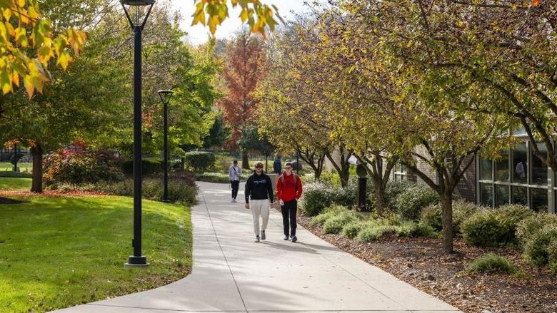 Two male students walk to class surrounded by fall foliage