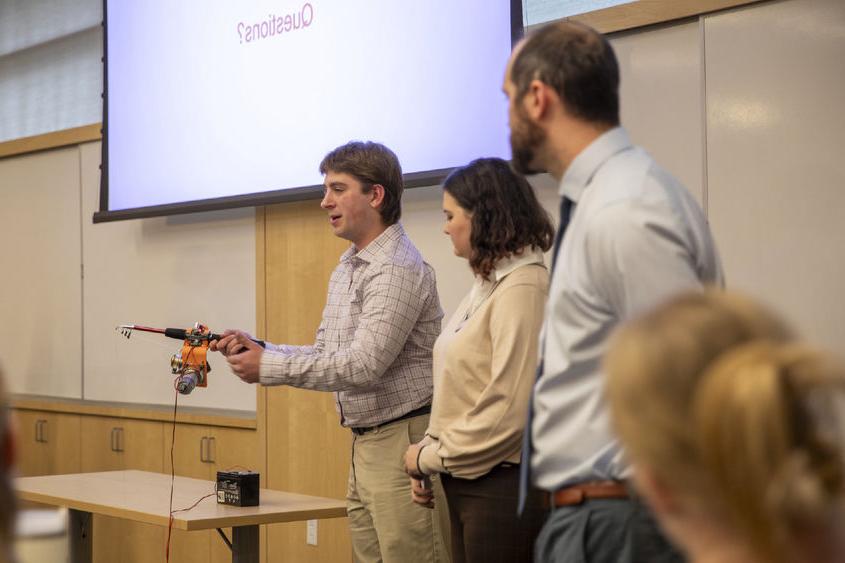 Male student showcases adaptive fishing rod.